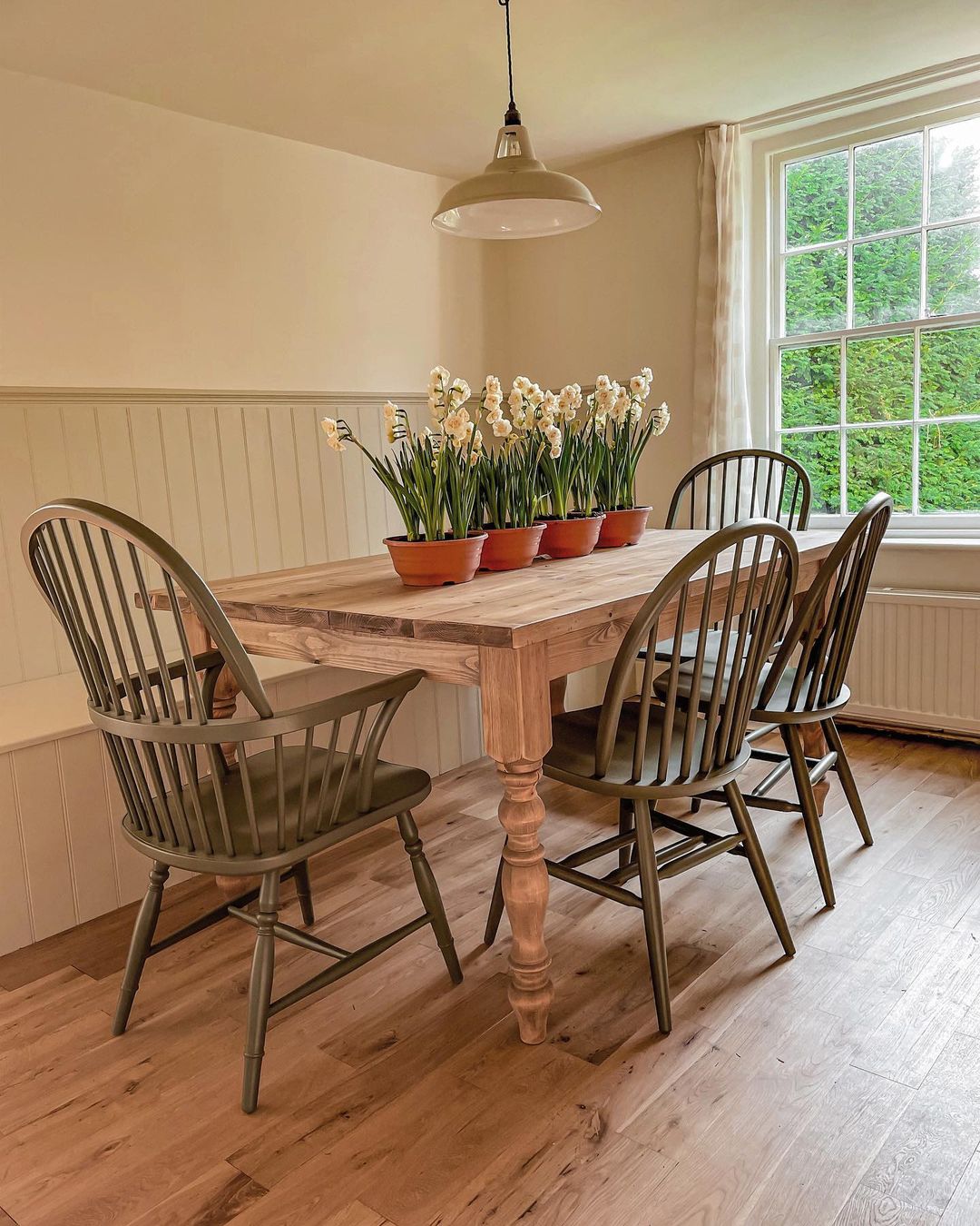 painted windsor dining chairs and a traditional farmhouse table in a cottage dining room